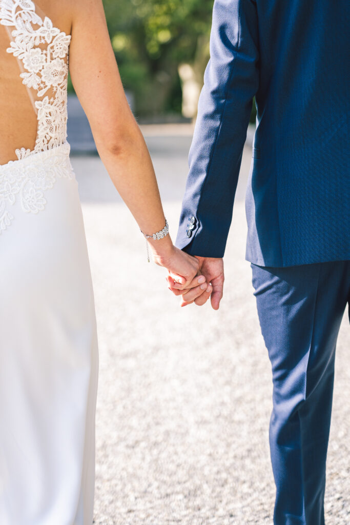 Hochzeitsfoto - Brautpaar Hand in Hand von hinten
